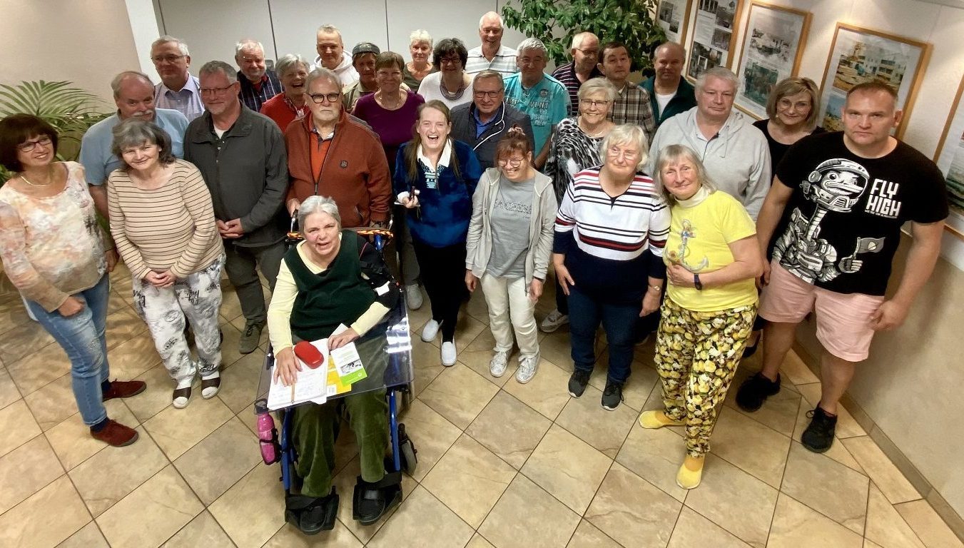 Gruppenfoto: Mitglieder der Selbsthilfegruppe, einige mit Rollstuhl und Rollator, lächeln in die Kamera